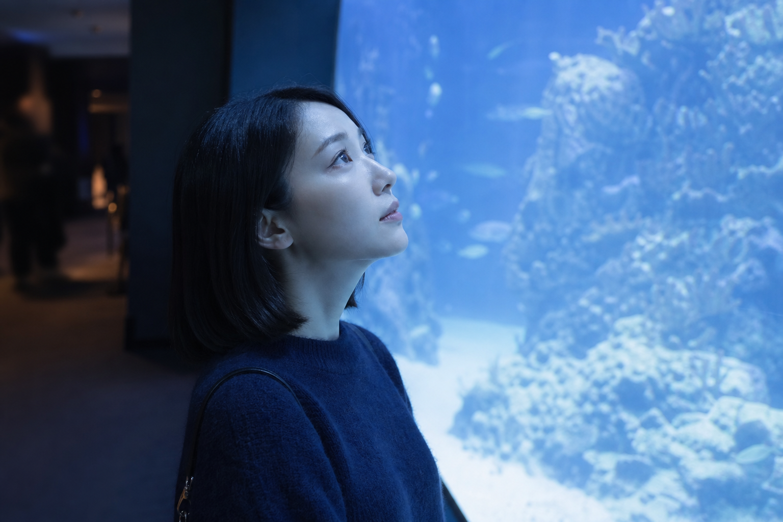 薄暗い水族館の水槽の前で
